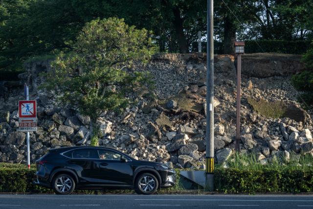 A car drives past the collapsed stone walls of the Yatsushiro Castle ruins in Yatsushiro, Kumamoto prefecture on July 30, 2026, following the July 28 earthquake. (Photo by Yuichi YAMAZAKI / AFP)