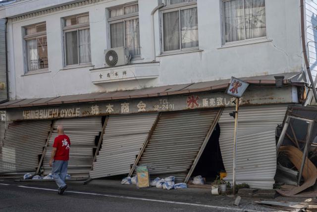 A man walks past a damaged building in Yatsushiro, Kumamoto prefecture on July 30, 2026, following the July 28 earthquake. (Photo by Yuichi YAMAZAKI / AFP)