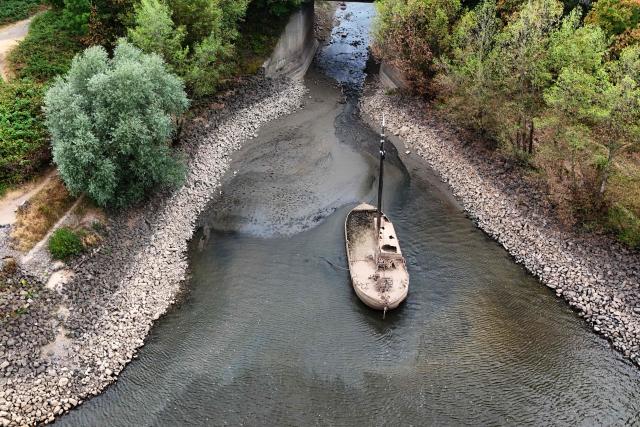 An aerial view shows a former eel fishing boat covered in dried mud among on low water among the banks of the river Rhine near Neuss, western Germany, on July 30, 2026, as the water level in the Rhine is falling to a record low following exceptionally hot weather. (Photo by Ina FASSBENDER / AFP)