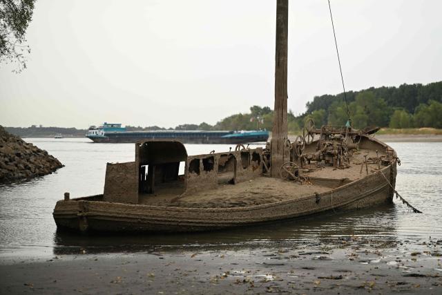 A former eel fishing boat covered in dried mud is seen on low water near the banks of the river Rhine near Neuss, western Germany, on July 30, 2026, as the water level in the Rhine is falling to a record low following exceptionally hot weather. (Photo by Ina FASSBENDER / AFP)