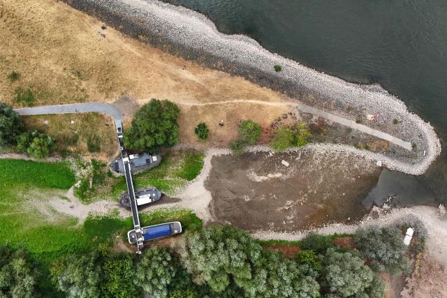 An aerial view shows three former vessels standing on dry land, including a sailing ship and an eel-fishing boat, connected by a bridge now serving as a café for day-trippers, at the old confluence of the River Wupper and the River Rhine near Leverkusen, western Germany on July 30, 2026, following exceptionally hot weather. The ship bridge at the confluence of the Wupper and the Rhine is a historic ship bridge consisting of three ships named "Unity, justice and freedom" (Einigkeit, Recht and Freiheit), which are connected by a gangway. (Photo by Ina FASSBENDER / AFP)