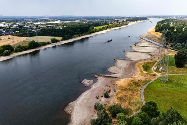 An aerial view shows vessels navigate on the centre of the river among partly dried-up banks of the Rhine near Leverkusen, western Germany on July 30, 2026, following exceptionally hot weather. (Photo by Ina FASSBENDER / AFP)