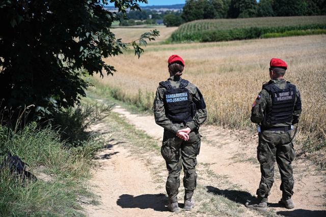 Police officers of the "Military Gendarmerie" stand guard in an area near the village of Tarnawa-Kolonia, eastern Poland, 30 July 2026, where a flying object hit the ground and exploded in the early hours of the day, the fire service reported. Residents of this locality in the Lublin region heard, shortly before 4:00 a.m. (2:00 a.m. GMT), a powerful explosion that shook the windows of their homes. The impact site is located around 80 km from the Ukrainian border. NATO said on July 30 it was in close contact with Warsaw as it blamed Russia for a missile that crashed in Poland, and vowed to "continue to take all necessary measures to defend" alliance territory. (Photo by Wojtek JARGILO / PAP / AFP) / Poland OUT