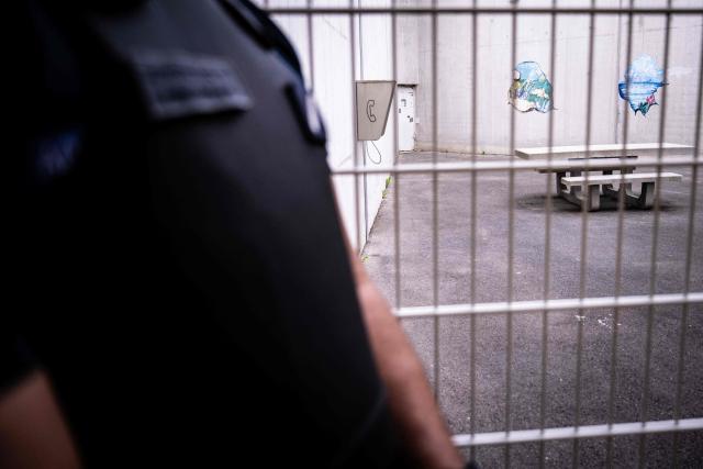 A prison officer stands in front of the outdoor courtyard at the third organised crime unit (drug-trafficking district) during a press tour at Reau Prison, near Paris on July 30, 2026. A third organised crime unit is set to open in France in the coming weeks, at Réau prison (Seine-et-Marne), one year after the first such unit opened in Pas-de-Calais, the prison service announced on July 30, 2026 during a press tour of the facility. (Photo by Lou BENOIST / AFP)