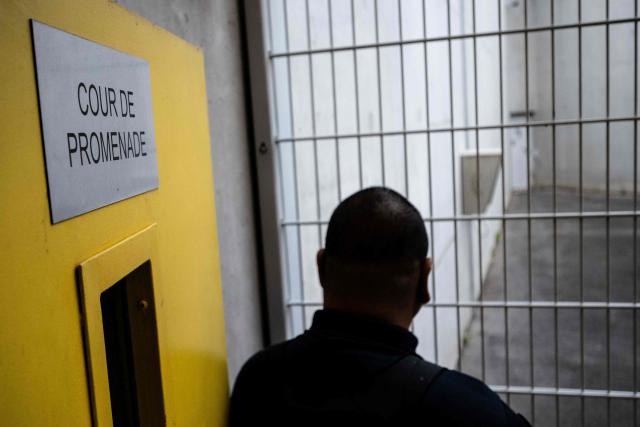 A prison officer stands in front of the outdoor courtyard at the third organised crime unit (drug-trafficking district) during a press tour at Reau Prison, near Paris on July 30, 2026. A third organised crime unit is set to open in France in the coming weeks, at Réau prison (Seine-et-Marne), one year after the first such unit opened in Pas-de-Calais, the prison service announced on July 30, 2026 during a press tour of the facility. (Photo by Lou BENOIST / AFP)