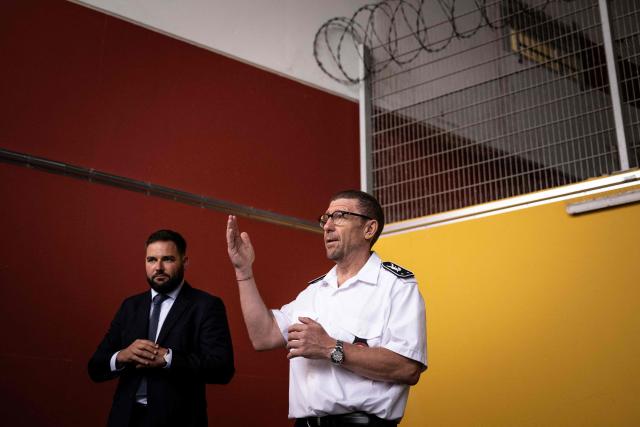 Olivier Pipino (C), Reau prison director, standing next to the spokesperson for the Ministry of Justice, Sacha Straub-Kahn, gestures as he speaks at the third organised crime unit (drug-trafficking district) during a press tour at Reau Prison, near Paris on July 30, 2026. A third organised crime unit is set to open in France in the coming weeks, at Réau prison (Seine-et-Marne), one year after the first such unit opened in Pas-de-Calais, the prison service announced on July 30, 2026 during a press tour of the facility. (Photo by Lou BENOIST / AFP)