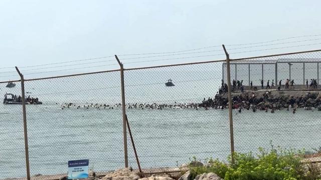 This video frame grab obtained from an AFP video shows migrants swimming in the sea to reach the shore of Spanish north African exclave of Ceuta, in Ceuta on July 30, 2026. Hundreds of migrants entered the Spanish north African exclave of Ceuta today, AFP reporters saw, many of them having swum by sea around the frontier fence. Migration from Morocco into Spain's two north African territories, Ceuta and Melilla, has long been a politically sensitive issue between the two countries, as thousands cross the border at times. AFP reporters saw a stream of adults and children, most of them wet, entering the town. (Photo by Lucía DIAZ / AFP)
