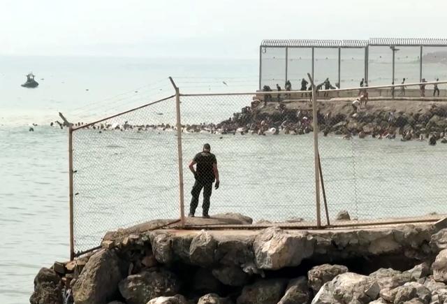 This video frame grab obtained from an AFP video shows migrants swimming in the sea to reach the shore of Spanish north African exclave of Ceuta, in Ceuta on July 30, 2026. Hundreds of migrants entered the Spanish north African exclave of Ceuta today, AFP reporters saw, many of them having swum by sea around the frontier fence. Migration from Morocco into Spain's two north African territories, Ceuta and Melilla, has long been a politically sensitive issue between the two countries, as thousands cross the border at times. AFP reporters saw a stream of adults and children, most of them wet, entering the town. (Photo by Lucía DIAZ / AFP)