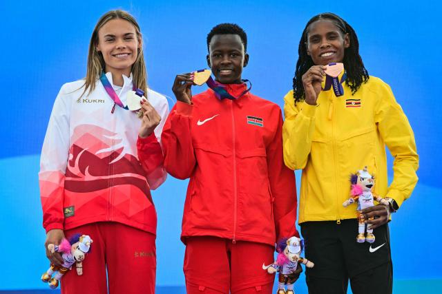 (From L) Silver medallist England's Elise Thorner, gold medallist Kenya's Faith Cherotich and bronze medallist Uganda's Peruth Chemutai celebrate on the podium after competing in the women's 3000m steeplechase during the athletics event at the Scotstoun Stadium in Glasgow, on day seven of the Commonwealth Games in Glasgow, Scotland, on July 30, 2026. (Photo by ANDY BUCHANAN / AFP)
