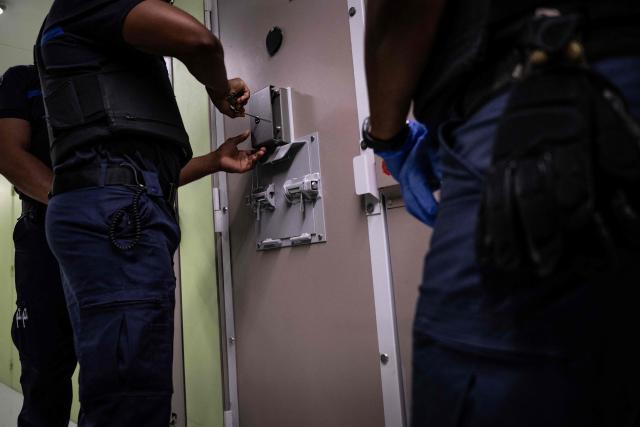 A prison officer demonstrates how to open a cell door at the third organised crime unit (drug-trafficking district) during a press tour at Reau Prison, near Paris on July 30, 2026. A third organised crime unit is set to open in France in the coming weeks, at Réau prison (Seine-et-Marne), one year after the first such unit opened in Pas-de-Calais, the prison service announced on July 30, 2026 during a press tour of the facility. (Photo by Lou BENOIST / AFP)