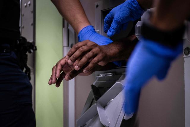 A prison officer handcuffs a colleague as part of a drill at the third organised crime unit (drug-trafficking district) during a press tour at Reau prison, near Paris on July 30, 2026. A third organised crime unit is set to open in France in the coming weeks, at Reau prison (Seine-et-Marne), one year after the first such unit opened in Pas-de-Calais, the prison service announced on July 30, 2026 during a press tour of the facility. (Photo by Lou BENOIST / AFP)