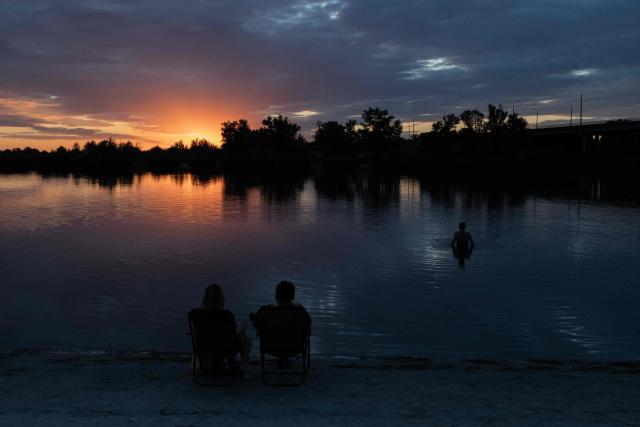 A person swims in a river at sunset during an air raid alert outside the city of Dnipro on July 30, 2026, amid the Russian invasion of Ukraine. (Photo by Roman PILIPEY / AFP)