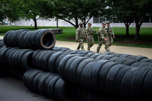 Members of the National Guard walk past piles of tires that will be as protective walls for the Freedom 250 Grand Prix along the National Mall in Washington, DC on July 30, 2026. The Freedom 250 Grand Prix is an IndyCar Series races scheduled for August 22–23, 2026 around the National Mall, to celebrate the 250th anniversary of the US Independence. (Photo by Kent Nishimura / AFP)