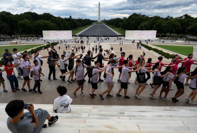 Visitors form a spontaneous dance line on the steps of the Lincoln Memorial backdropped by the Reflecting Pool on the National Mall in Washington, DC on July 30, 2026. The renovation of the pool next to Lincoln Memorial is a pet project of US President Donald Trump's, but the remodel has been dogged by the growth of algae and peeling paint which the president alleges is the work of vandals. (Photo by Kent Nishimura / AFP)