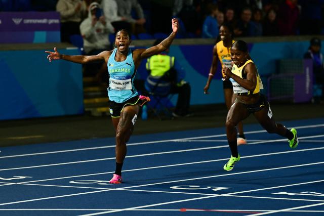 Winner Bahamas' Devynne Charlton (L) celebrates as she crosses the finish line past second-placed Jamaica's Megan Simmonds (R) in the women's 100m hurdles final during the athletics event at the Scotstoun Stadium in Glasgow, on day seven of the Commonwealth Games in Glasgow, Scotland, on July 30, 2026. (Photo by Ben STANSALL / AFP)