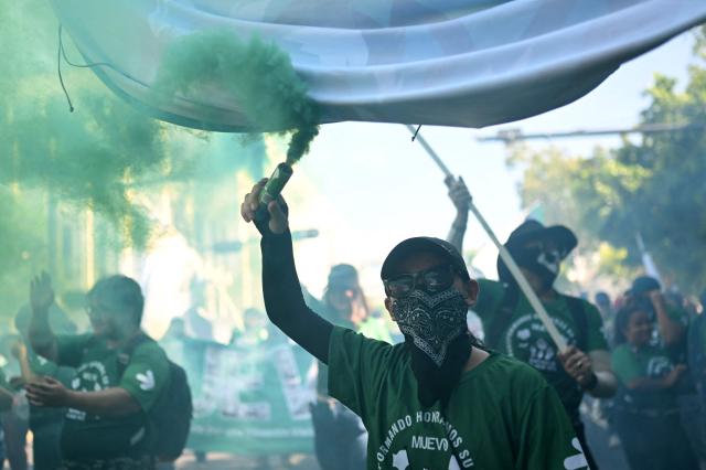 Demonstrators light green smoke flares during a march marking the 51st anniversary of the 1975 Salvadoran student massacre in San Salvador on July 30, 2026. On July 30, 1975, a protest march against the military occupation of a campus of the state-run University of El Salvador (UES) was dispersed by police using armored vehicles and gunfire during the administration of late Colonel Arturo Armando Molina (1972-1977), with university authorities reporting that around 50 students were killed and dozens disappeared. (Photo by Marvin RECINOS / AFP)