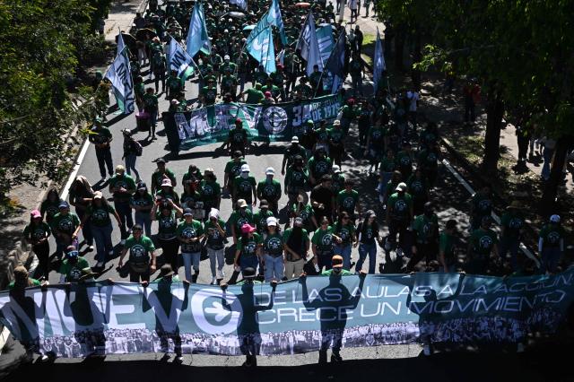 Demonstrators take part in a march to commemorate the 51st anniversary of the 1975 Salvadoran student massacre in San Salvador on July 30, 2026. On July 30, 1975, a protest march against the military occupation of a campus of the state-run University of El Salvador (UES) was dispersed by police using armored vehicles and gunfire during the administration of late Colonel Arturo Armando Molina (1972-1977), with university authorities reporting that around 50 students were killed and dozens disappeared. (Photo by Marvin RECINOS / AFP)