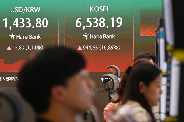 Dealers work near an electronic screen showing South Korea's benchmark stock index (KOSPI) in a foreign exchange dealing room at the Hana Bank headquarters in Seoul on July 31, 2026. South Korean stocks jumped 13 percent at open on July 31 with tentpole AI chipmaker SK hynix surging 20 percent, rebounding after a week of bruising losses. (Photo by GREG BAKER / AFP)