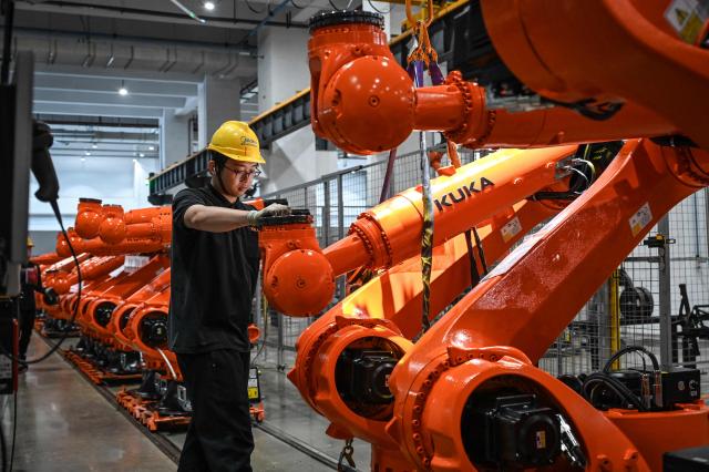 (FILES) The photo taken on March 17, 2026 shows a worker working on an industrial robot assembly line at a KUKA factory in Foshan, in southern Guangdong province. China's factory activity slumped in July, official data showed on July 31, 2026 as leaders in the world's second-largest economy struggle to reignite domestic demand. (Photo by Jade GAO / AFP)