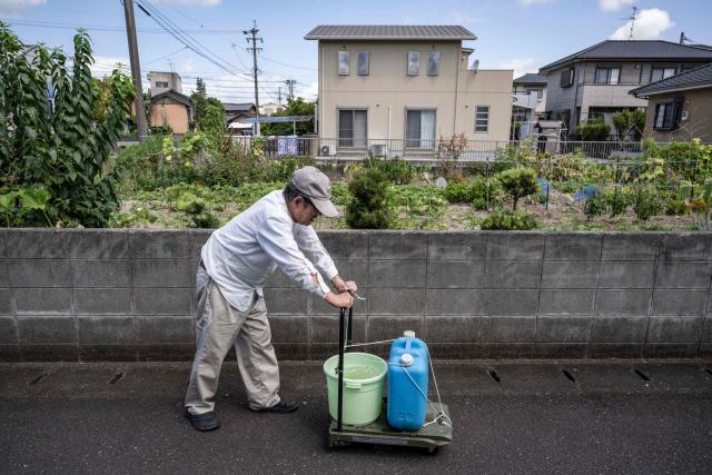 An elderly man uses a cart to carry water collected from a river following the the July 28 earthquake, in Yatsushiro, Kumamoto prefecture on 31 July 2026. (Photo by Yuichi YAMAZAKI / AFP)
