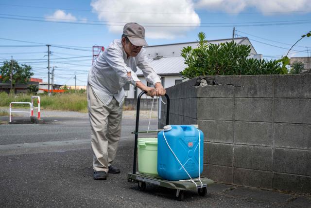 An elderly man uses a cart to carry water collected from a river following the the July 28 earthquake, in Yatsushiro, Kumamoto prefecture on 31 July 2026. (Photo by Yuichi YAMAZAKI / AFP)