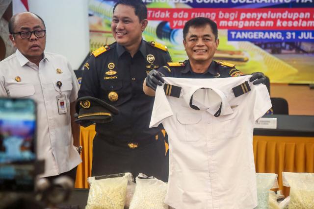 Indonesian Customs officials display the uniform of a Malaysian pilot and drugs he smuggled as evidence during a press conference at Soekarno-Hatta International Airport in Tangerang, near Jakarta, on July 31, 2026. A 39-year-old pilot, identified only by his initials MSO, was arrested shortly after arriving from Kuala Lumpur for allegedly carrying over 70,000 ecstasy tablets and meth in his suitcase. Police confirmed the pilot also tested positive for drugs while operating the passenger plane. (Photo by Ramu / AFP)
