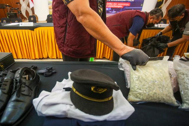 Indonesian Customs officials prepare to display the uniform of a Malaysian pilot and drugs he smuggled as evidence before a press conference at Soekarno-Hatta International Airport in Tangerang, near Jakarta, on July 31, 2026. A 39-year-old pilot, identified only by his initials MSO, was arrested shortly after arriving from Kuala Lumpur for allegedly carrying over 70,000 ecstasy tablets and meth in his suitcase. Police confirmed the pilot also tested positive for drugs while operating the passenger plane. (Photo by Ramu / AFP)