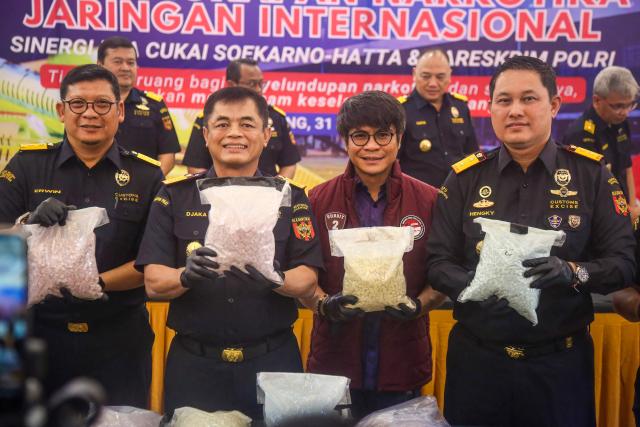 Indonesian Customs officials display drugs smuggled by a Malaysian pilot as evidence during a press conference at Soekarno-Hatta International Airport in Tangerang, near Jakarta, on July 31, 2026. A 39-year-old pilot, identified only by his initials MSO, was arrested shortly after arriving from Kuala Lumpur for allegedly carrying over 70,000 ecstasy tablets and meth in his suitcase. Police confirmed the pilot also tested positive for drugs while operating the passenger plane. (Photo by Ramu / AFP)
