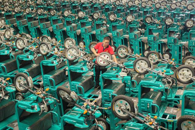 A staff member examines electric tricycles before shipment in Linyi city, China’s eastern Shandong province on July 30, 2026. (Photo by CN-STR / AFP) / China OUT