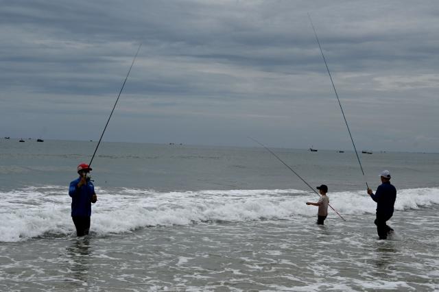 People fish at the beach in Da Nang on July 31, 2026. (Photo by Nhac NGUYEN / AFP)