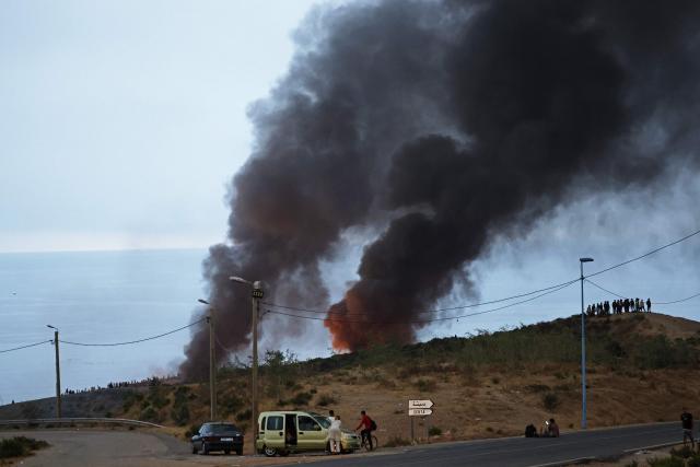 Smoke billows from the site of clashes near Fnideq, on the Morocco-Spain border, on July 31, 2026. Thousands of migrants crossed overnight from Morocco into Spain's north Africa's Ceuta enclave, a police source said on July 31, adding that it was impossible to estimate how many people in total. A total of 18 people died while attempting to reach the Spanish enclave, the source said. (Photo by Abdel Majid BZIOUAT / AFP)