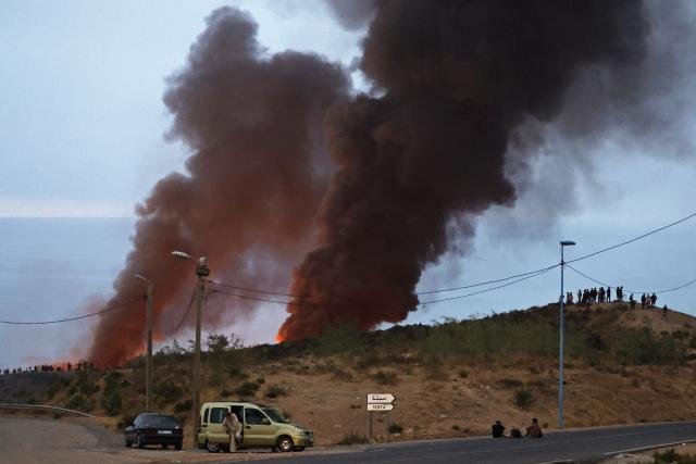 Smoke billows from the site of clashes near Fnideq, on the Morocco-Spain border, on July 31, 2026. Thousands of migrants crossed overnight from Morocco into Spain's north Africa's Ceuta enclave, a police source said on July 31, adding that it was impossible to estimate how many people in total. A total of 18 people died while attempting to reach the Spanish enclave, the source said. (Photo by Abdel Majid BZIOUAT / AFP)
