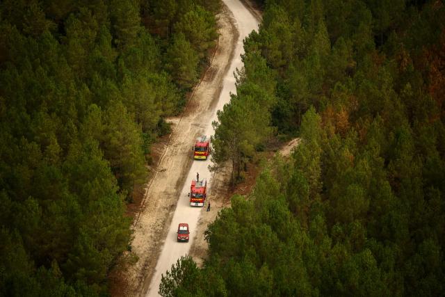 This aerial photograph taken from a French Civil Security rescue coordination helicopter shows firefighters' vehicles driving on road along a wooden area in Le Porge, south-western France on July 31, 2026, as a wildfire has been ravaging the forest north of the Arcachon Basin (Gironde) since July 22. (Photo by Sarah Meyssonnier / POOL / AFP)
