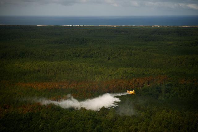 This aerial photograph taken from a French Civil Security rescue coordination helicopter shows a Turkish Air Tractor AT-802F Fire Boss amphibious water bomber A-172 dropping a load of water over a wildfire in Le Porge, south-western France on July 31, 2026, as a wildfire has been ravaging the forest north of the Arcachon Basin (Gironde) since July 22. (Photo by Sarah Meyssonnier / POOL / AFP)
