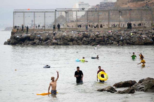 Migrants swim through the waters close to the border with Morocco to enter Spain's north Africa's Ceuta enclave on July 31, 2026. Thousands of migrants crossed overnight from Morocco into Ceuta enclave, a police source said, as Spanish Prime Minister was set to arrive to manage the latest migrant crisis on the border. In recent days, a total of around 40,000 migrants have crossed into the territory, population 80,000, the source added. (Photo by JORGE GUERRERO / AFP)