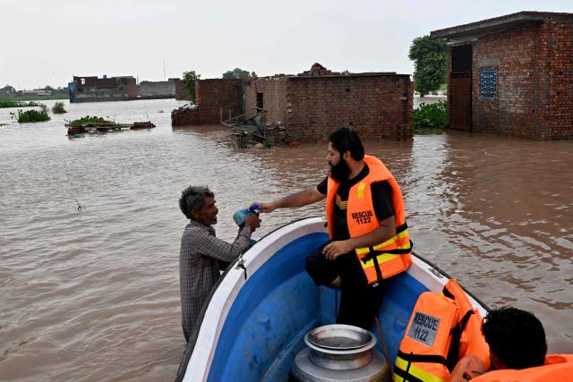 Rescue personnel distribute food in a flooded area after the Ravi river overflowed following heavy monsoon rains on the outskirts of Lahore on July 31, 2026. (Photo by Arif ALI / AFP)