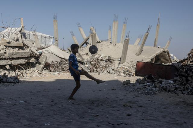 A Palestinian boy juggles a ball in front of a destroyed building in Khan Yunis in the southern Gaza Strip on July 31, 2026. Hamas said on July 31, 2026, it had agreed to a deal announced by the US president to end its war with Israel, which includes it handing over its weapons to a Palestinian governing committee and the gradual withdrawal of Israeli forces from Gaza. (Photo by Bashar Taleb / AFP)
