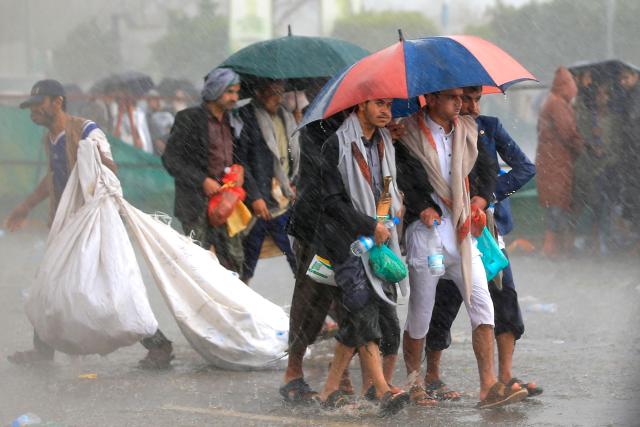 Protesters take cover under their umbrellas during a downpour as they demonstrated against the Saudi-led coalition in Sanaa on July 31, 2026. (Photo by Mohammed HUWAIS / AFP) / 