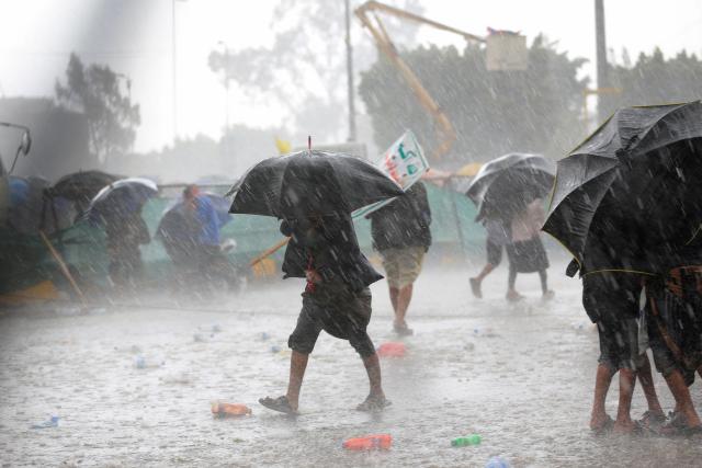 Protesters take cover under their umbrellas  during a downpour as they demonstrated against the Saudi-led coalition in Sanaa on July 31, 2026. (Photo by Mohammed HUWAIS / AFP) / 