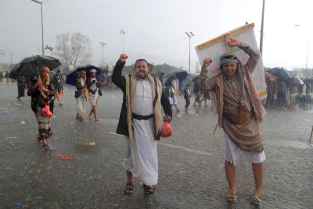 Protesters react as the take walk to take cover during a downpour as they demonstrated against the Saudi-led coalition in Sanaa on July 31, 2026. (Photo by Mohammed HUWAIS / AFP) / 