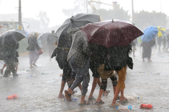 Protesters take cover under their umbrellas  during a downpour as they demonstrated against the Saudi-led coalition in Sanaa on July 31, 2026. (Photo by Mohammed HUWAIS / AFP) / 