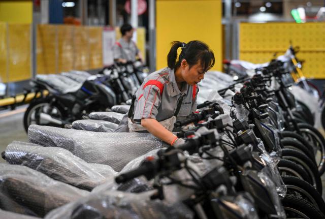 This picture taken on July 21, 2026 shows a worker checking motorcycles at the Shineray factory in Chongqing, southwestern China. The roar of engines fills the night air in China's Chongqing city as tourists awkwardly clamber onto gleaming motorbikes and cling to muscular drivers to star in personalised videos. Chongqing has been an industry hub since 1979, when state-owned military equipment manufacturer Jialing began producing civilian motorcycles in the city. Motorbikes quickly became popular, and the city now accounts for more than a third of China's total motorbike production. (Photo by WANG Zhao / AFP) / To go with 'CHINA-MOTORBIKE-INTERNET,FOCUS' by Sam DAVIES
