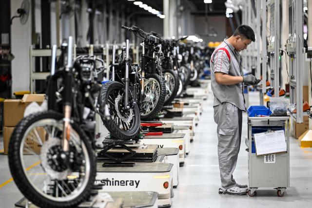 This picture taken on July 21, 2026 shows a worker preparing to assemble motorcycles at the Shineray factory in Chongqing, southwestern China. The roar of engines fills the night air in China's Chongqing city as tourists awkwardly clamber onto gleaming motorbikes and cling to muscular drivers to star in personalised videos. Chongqing has been an industry hub since 1979, when state-owned military equipment manufacturer Jialing began producing civilian motorcycles in the city. Motorbikes quickly became popular, and the city now accounts for more than a third of China's total motorbike production. (Photo by WANG Zhao / AFP) / To go with 'CHINA-MOTORBIKE-INTERNET,FOCUS' by Sam DAVIES