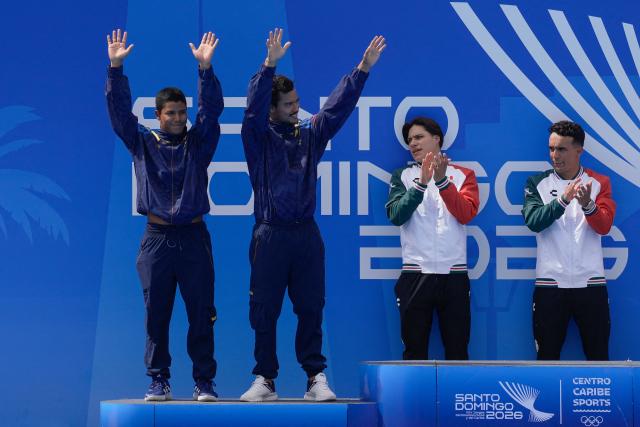 Colombian Luis Uribe (L) and Sebastian Morales (2-L) celebrate on the podium after getting the silver medal in the Men's Synchronised 3m Springboard competition, as the winners, Mexican Juan Celaya (R) and Osmar Olvera (2-R), applaud during the XXV Central American and Caribbean Games in Santo Domingo on July 31, 2026. (Photo by Francesco SPOTORNO / AFP)