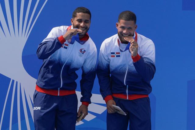 Dominican Frandiel Gomez (R) and Jose Calderon celebrate on the podium after getting the broze medal in the Men's Synchronised 3m Springboard competition during the XXV Central American and Caribbean Games in Santo Domingo on July 31, 2026. (Photo by Francesco SPOTORNO / AFP)