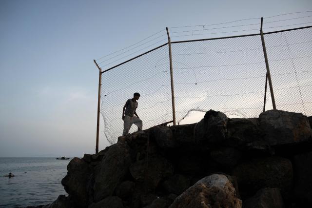 A migrant walks along a rocky shoreline near the border with Morocco after swimming towards Spain's North African enclave of Ceuta on July 31, 2026. Thousands of migrants crossed overnight from Morocco into Ceuta, according to a police source, as the Spanish prime minister prepared to visit the territory amid the latest migration crisis at the border. About 40,000 migrants have entered the enclave in recent days, the source added, in a territory with a population of around 80,000. (Photo by JORGE GUERRERO / AFP)