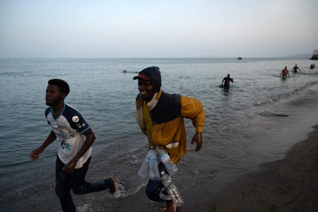 Migrants arrive on the shore after swimming into the Spanish enclave of Ceuta in North Africa on July 31, 2026. Thousands of migrants crossed overnight from Morocco into Ceuta, according to a police source, as the Spanish prime minister prepared to visit the territory amid the latest migration crisis at the border. About 40,000 migrants have entered the enclave in recent days, the source added, in a territory with a population of around 80,000. (Photo by JORGE GUERRERO / AFP)