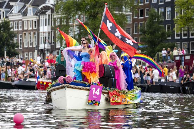 Participants on boats pass next to spectators on a canal as they take part in the Canal Parade of the Pride celebrations in Amsterdam on August 1, 2026. (Photo by Sem van der Wal / ANP / AFP) / Netherlands OUT