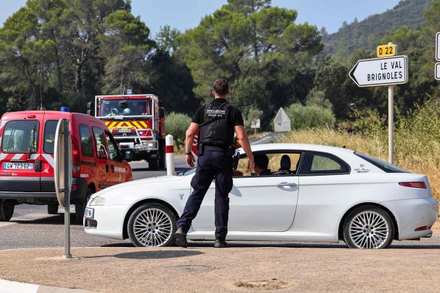 A French gendarme controls vehicles following a wildfire near Correns, southeastern France on August 1, 2026. In the Var department of south eastern France, the fire in the Gros Bessillon massif has flared up again and "grown in intensity," announced local prefect Simon Babre. The flames have swept across 1,000 hectares in six hours. This fire had been brought under control four days ago, after devastating 4,500 hectares. Forests catch fire all the more easily because the vegetation and soils have been extremely dry for months, a phenomenon exacerbated by climate change and the recent exceptional heatwaves. (Photo by CLEMENT MAHOUDEAU / AFP)