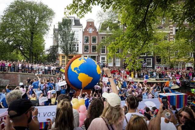 Participants on boats pass next to spectators on a canal as they take part in the Canal Parade of the Pride celebrations in Amsterdam on August 1, 2026. (Photo by Ramon van Flymen / ANP / AFP) / Netherlands OUT